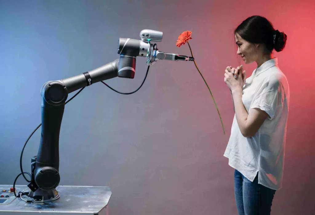 Petit manifeste pour une harmonie technologique - Un bras robotique donne une fleur rouge a une femme asiatique photo Pavel Danilyuk